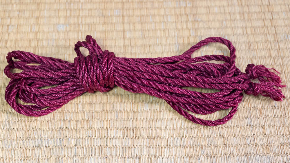 Final Image of a red shibari rope, hanked and sitting on a tatami matt