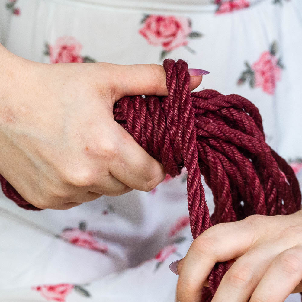 Hands neatly coiling shibari rope for storage and future rope play
