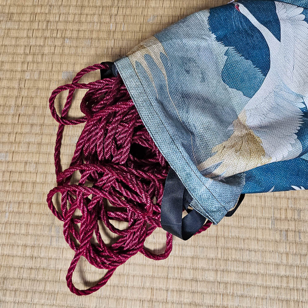 Red shibari rope uncoiled, to be hanked, falling out of a bag