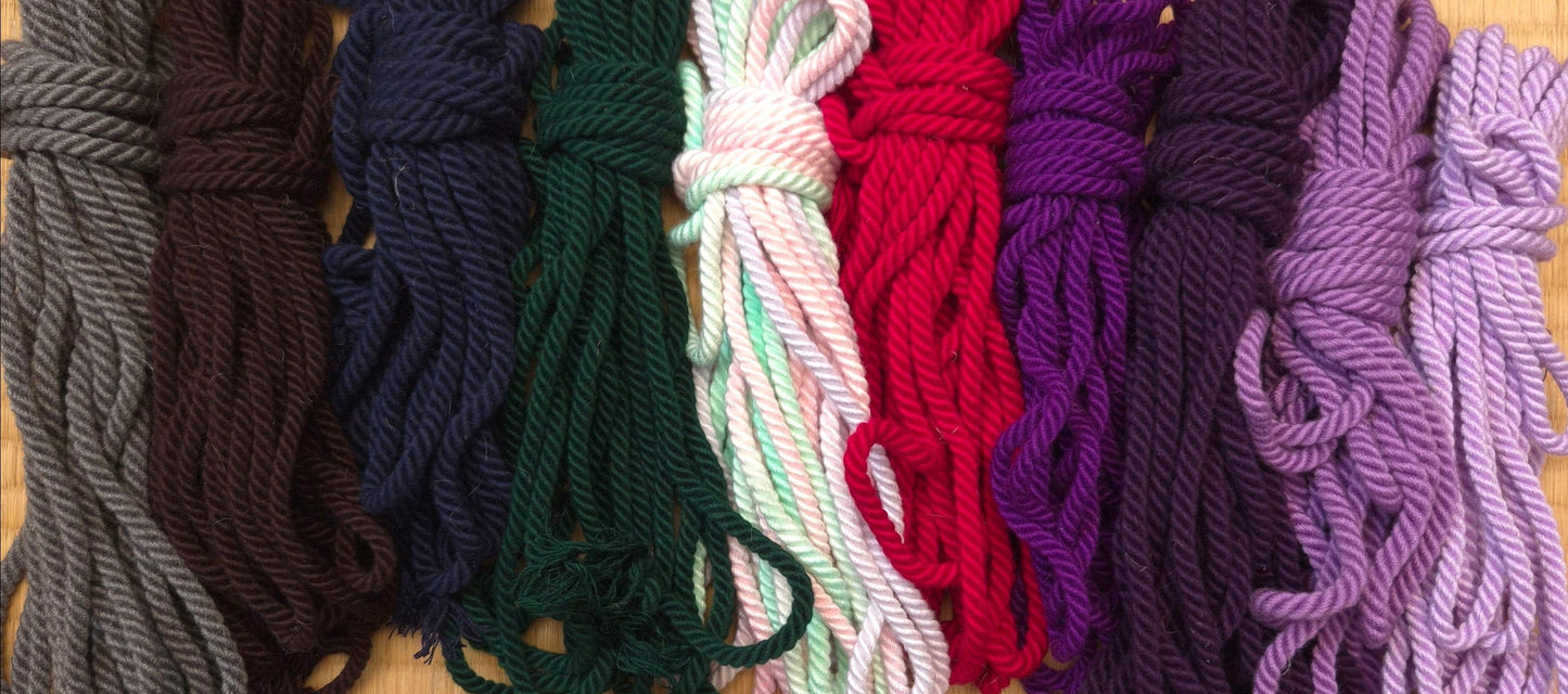 Stack of colourful yarn shibari ropes in various shades.
