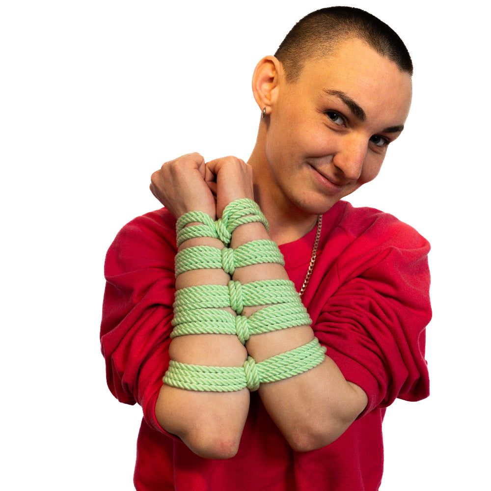 Person wearing a red hoodie with green rope束缚在手臂和腿上，背景为白色