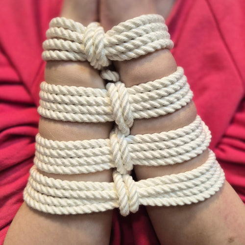 Person wearing Bamboo white rope bracelets on a blurred red background