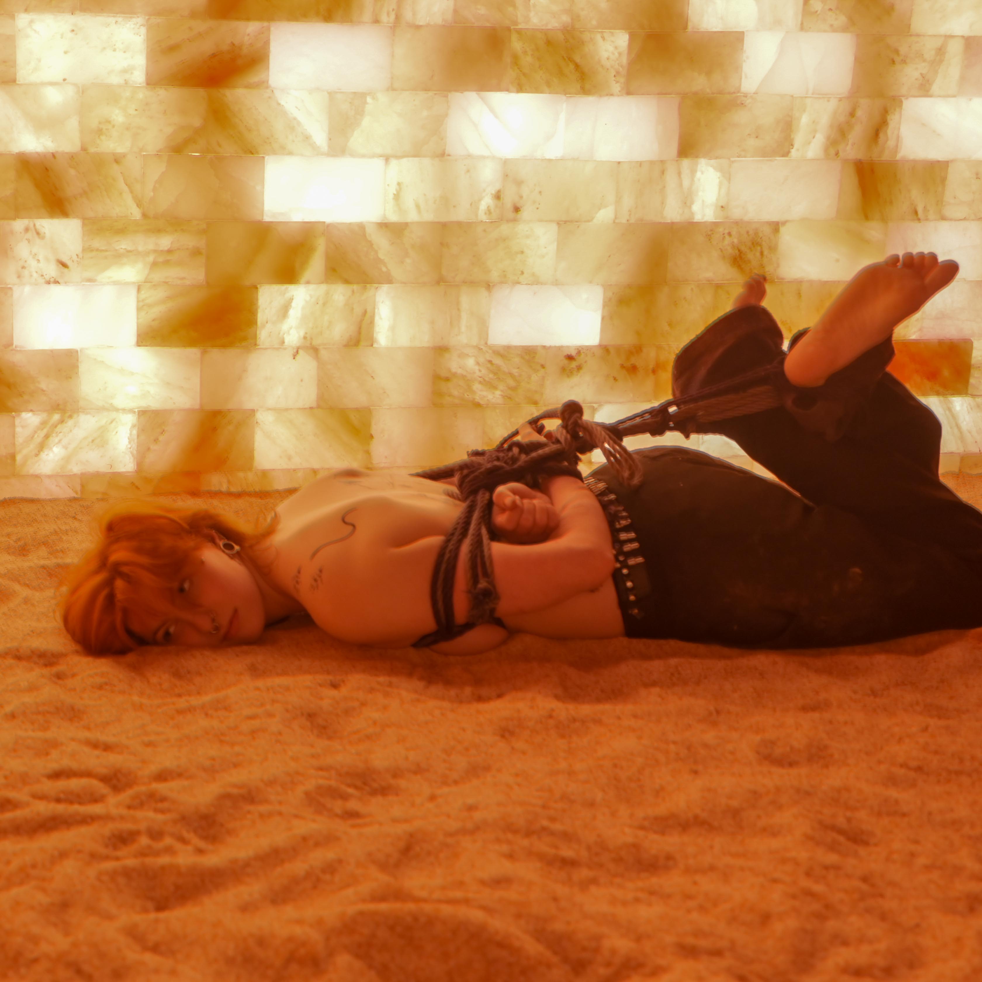 Red head women tied laying on sand