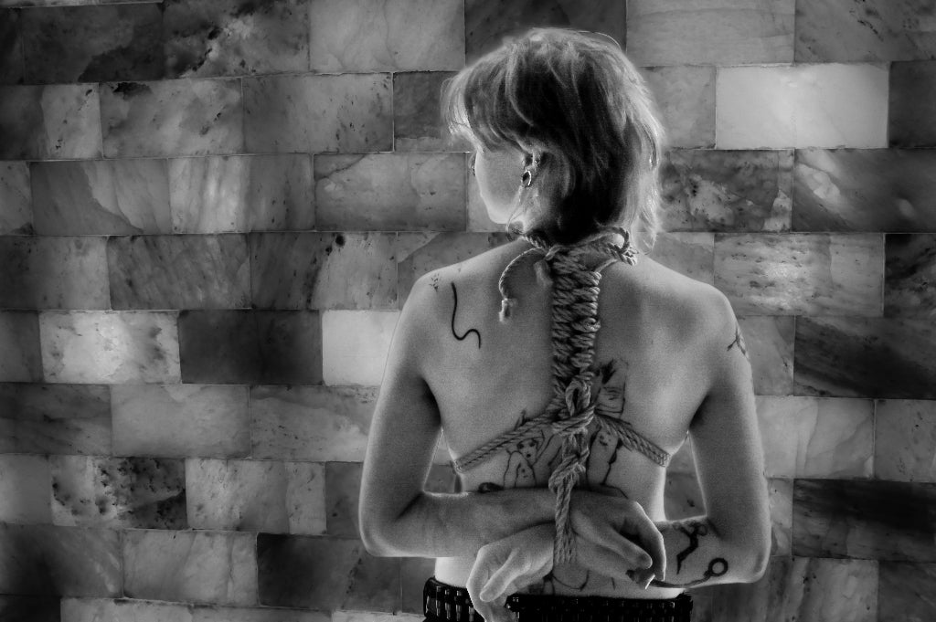 Black and white back view of tattooed women in shibari tie 