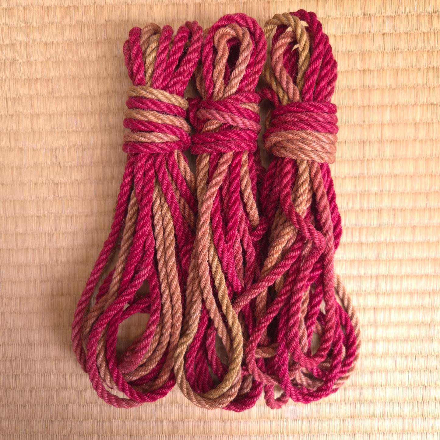 Three coils of red and brown rope on a tatami mat