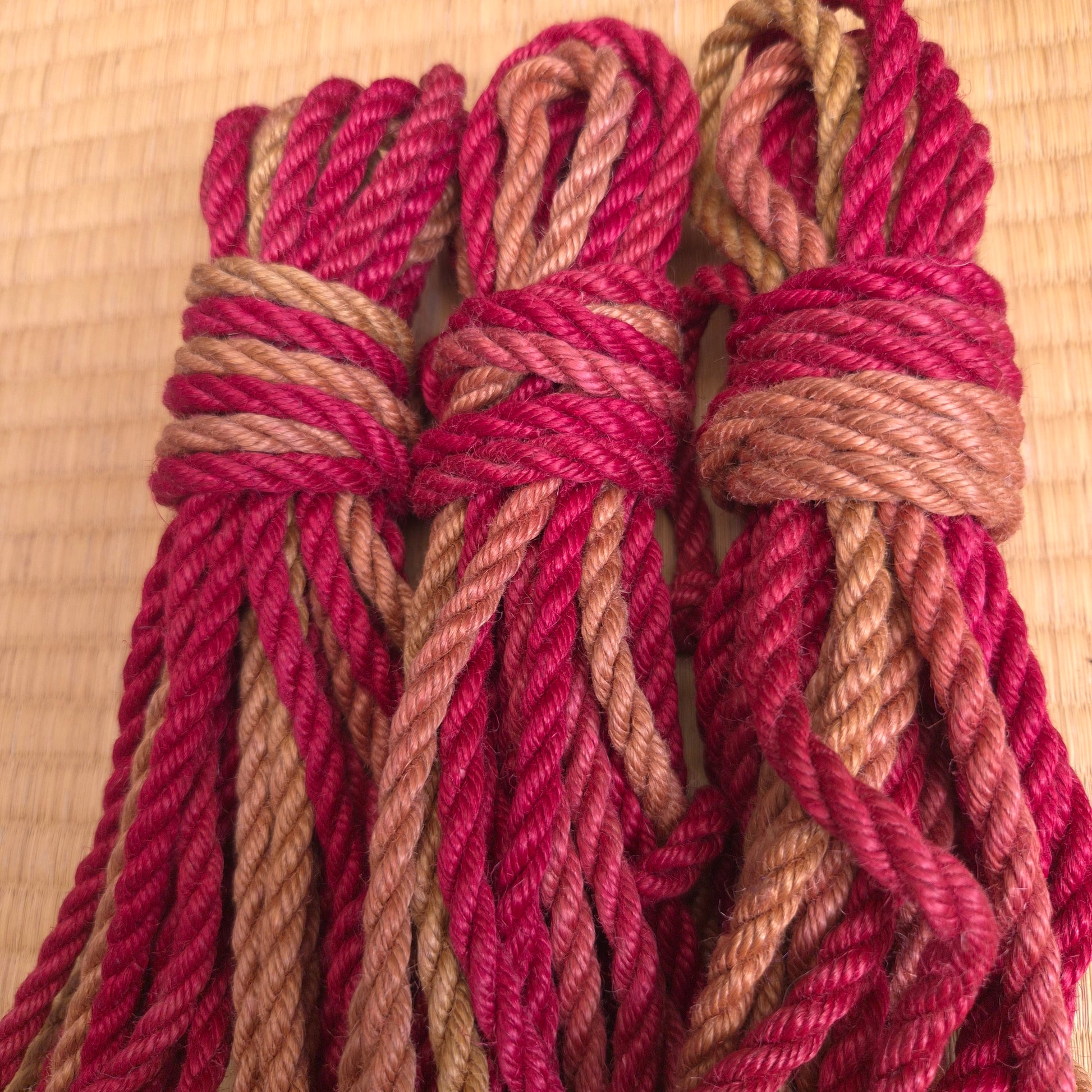 Close-up of red and brown rope tied in a knot on a tatami surface