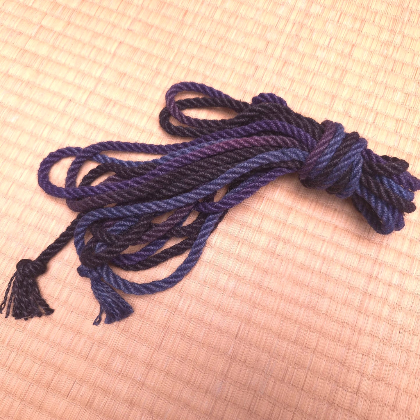 Coiled blue rope with tassels on a tatami  surface